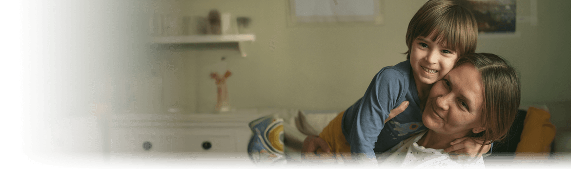 Smiling child hugging a parent indoors, conveying comfort and care at home